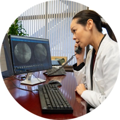 Female doctor talking on phone and looking at computer